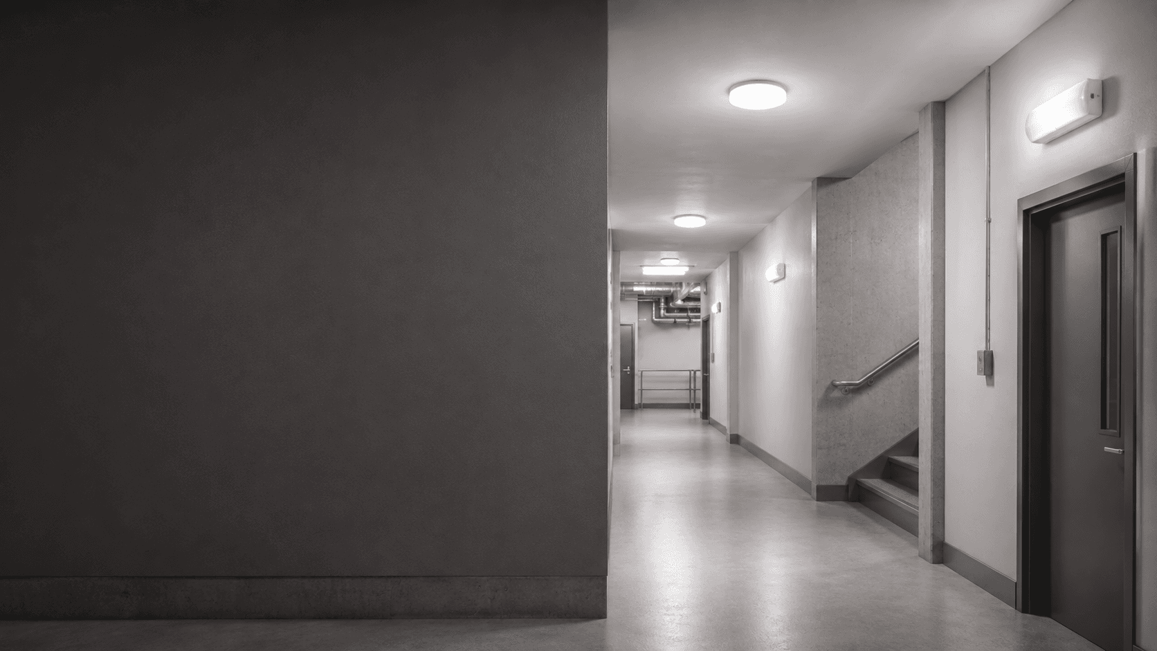 Professional building corridor with illuminated emergency exit guidance and emergency lighting