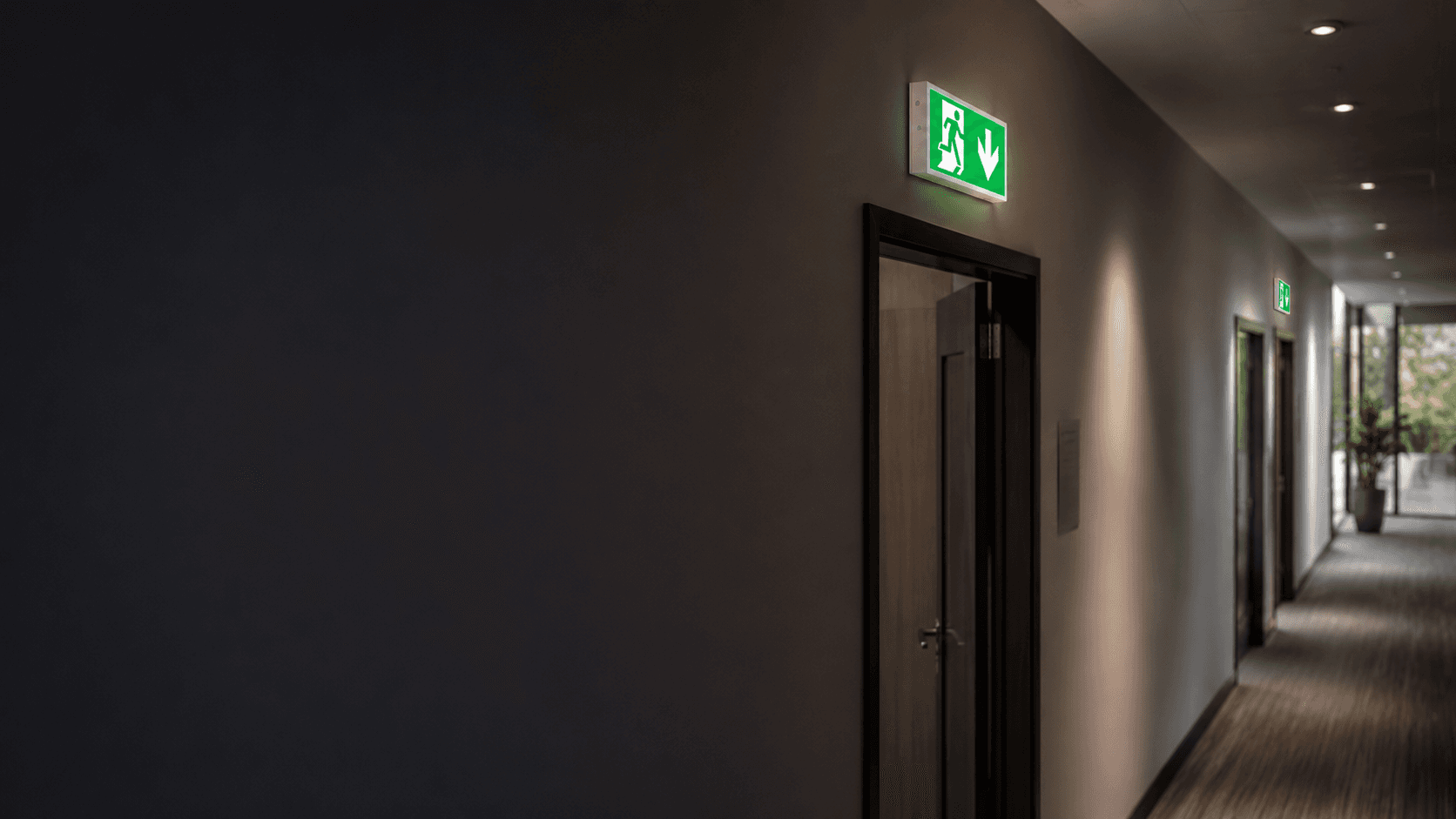 Professional building corridor with illuminated emergency exit guidance and emergency lighting