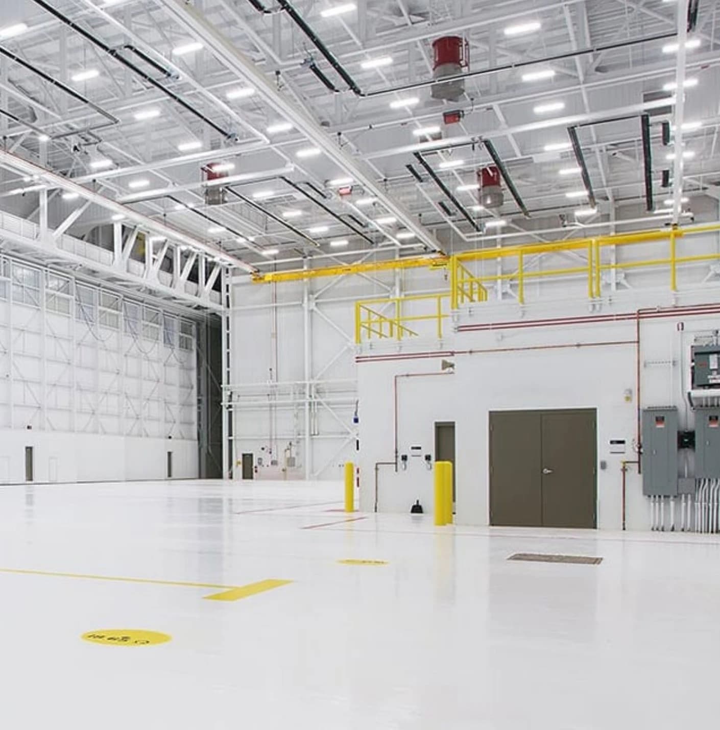 Large industrial high-bay hall lit by LED high-bay fixtures