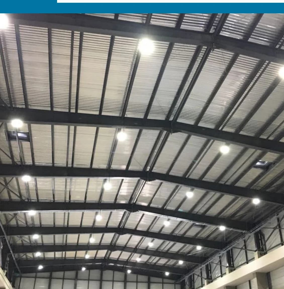 High-bay LED fixtures lighting a steel-framed industrial roof structure