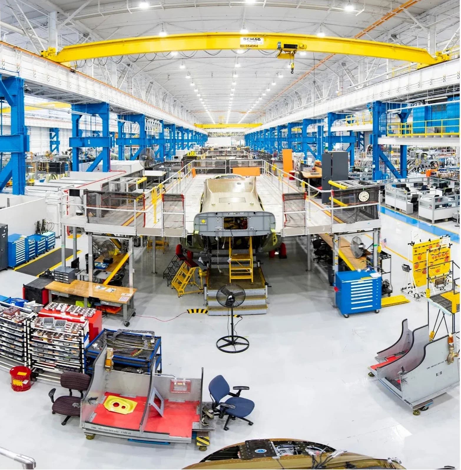 Aircraft assembly and maintenance hangar interior with an overhead gantry crane and technician workstations