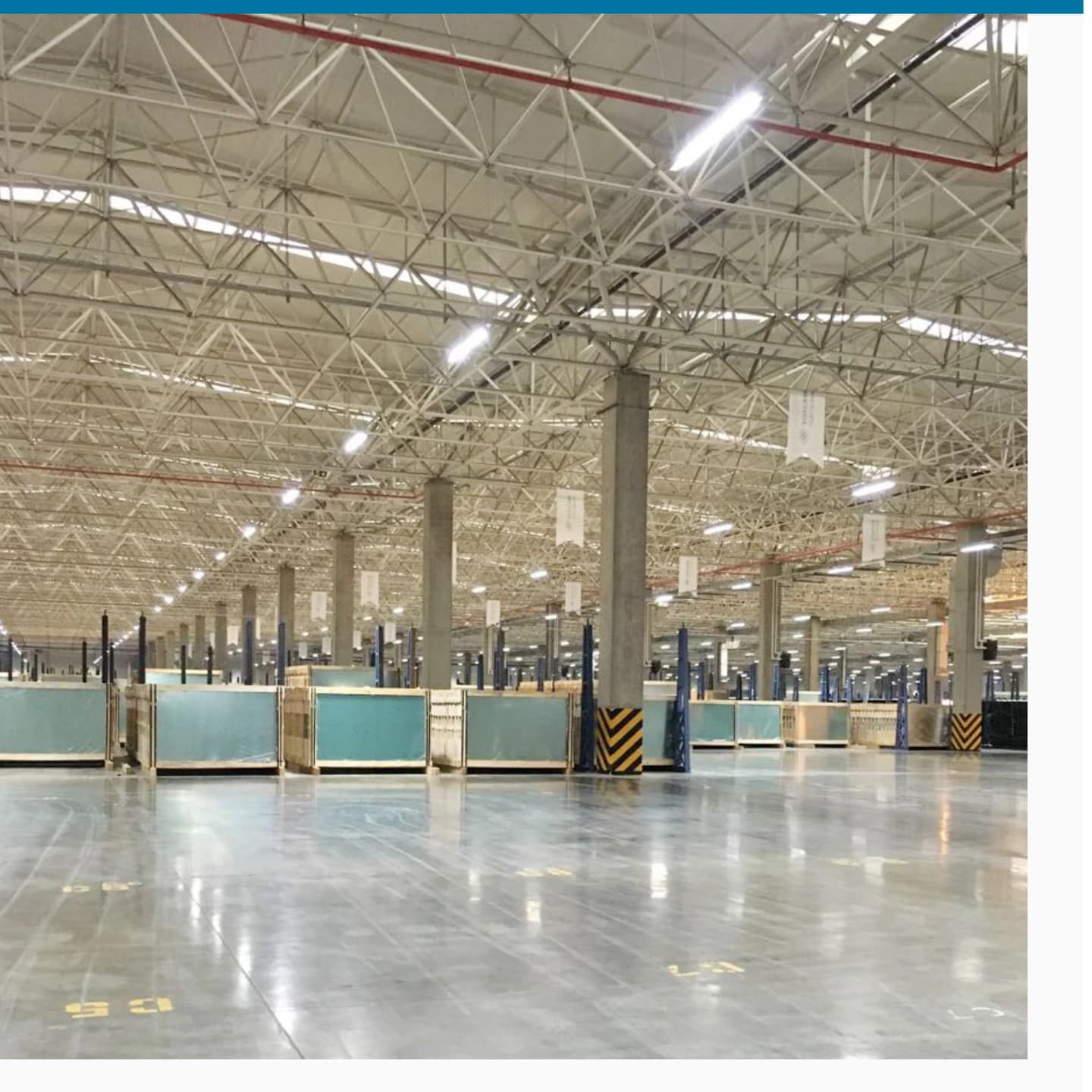 Large-span industrial hall interior with staged crated goods, lit by high-bay LED fixtures