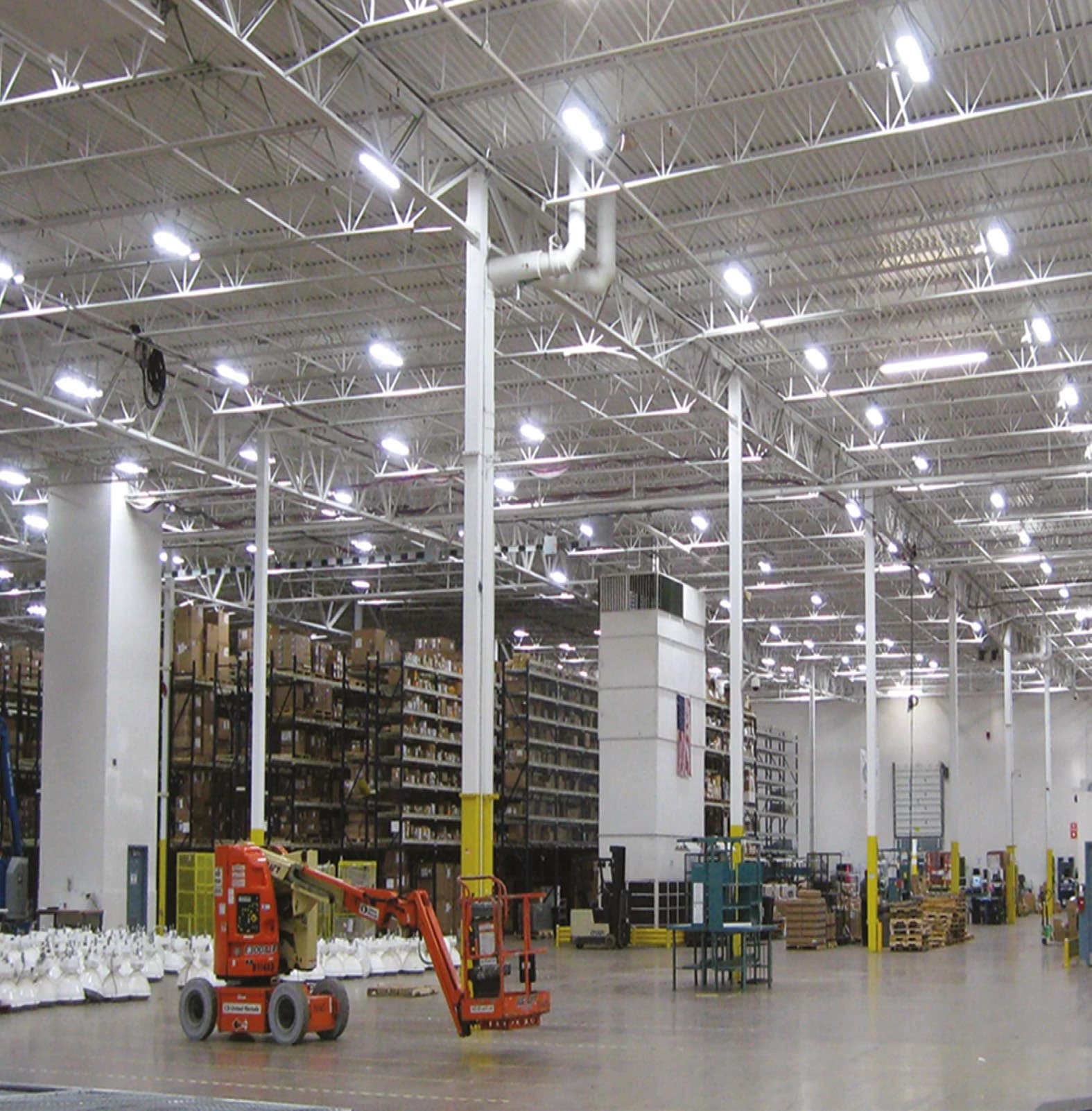 Warehouse aisle with pallet racking and a forklift, lit by high-bay LED fixtures
